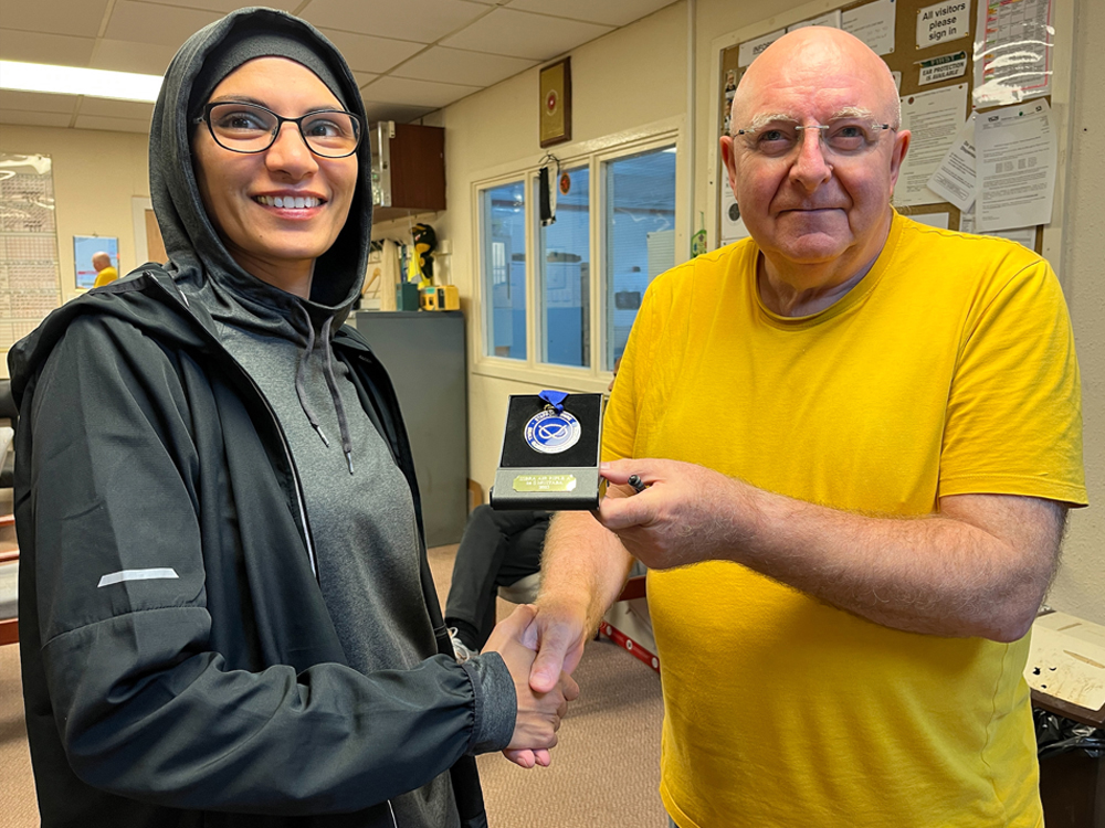 Photograph shows Shabana Mujtaba of Sutton Coldfield RPC (pictured left) receiving her SSRA Individual Air Rifle - A League - Summer 2025 - 1st Place Medal from Paul Stokes of Sutton Coldfield RPC (pictured right).