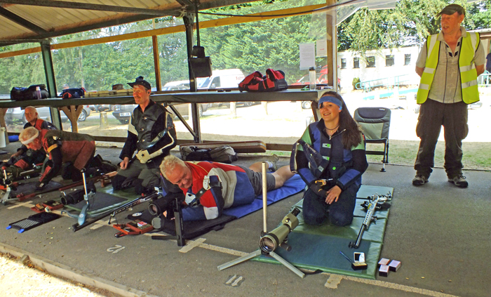 Photograph shows more competitors enjoying the event on the firing line, with smiles aplenty.
