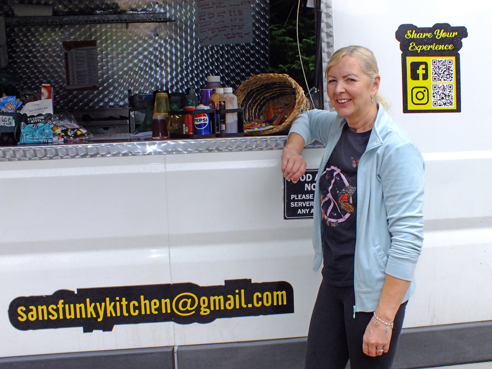 Photograph shows Sandra Williams, standing proudly alongside her beloved catering van.