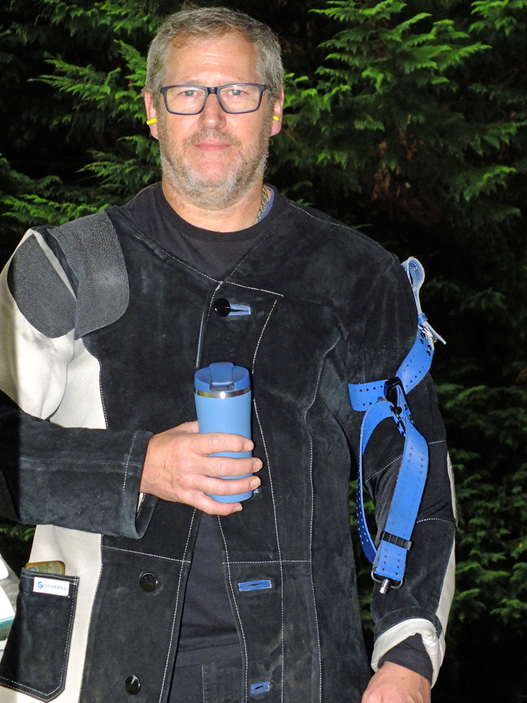 Photograph shows a suited and booted Paul Baron taking a last minute drink before his detail commences, pictured against the lush vegetation of the range in the background.