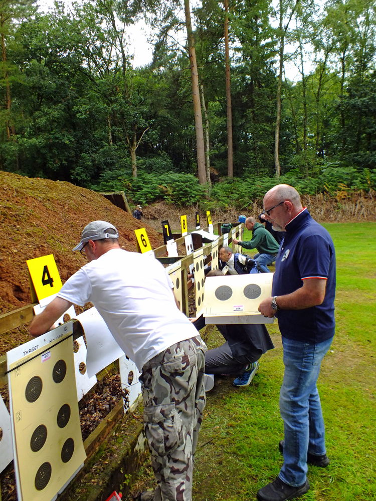 Photograph shows a flurry of activity on the 50 metres range, as new targets are carefully set up.