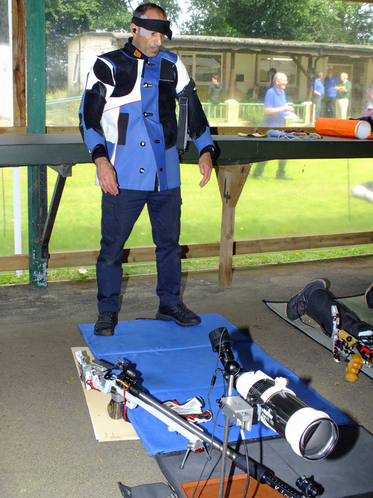 Photograph shows Kosta Loukas getting "in the zone" as he stands behind his array of kit on the firing line.
