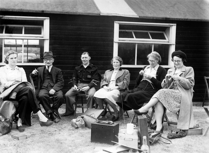 Photograph shows the social side of a shooting club, as the ladies relax outside the clubhouse - knitting, nattering and relaxing, while the chaps take a break too.