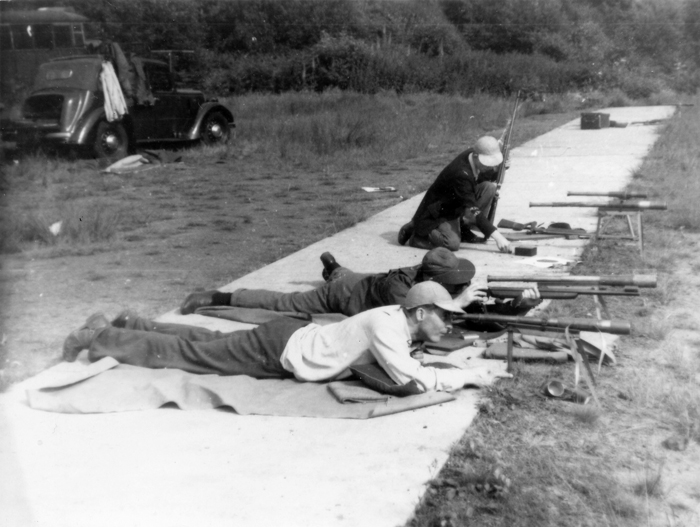 Photograph shows competitors settling down prior to shooting on the exposed firing points.