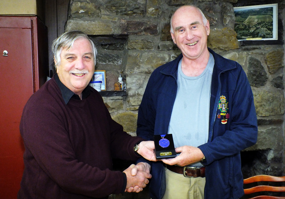 Photograph shows John Cooper of Leek and District Shooting Centre (pictured right) receiving his SSRA Individual 10 Metres Air Pistol - 'A' League - Summer 2026 - 3rd Place Medal from Osborn J Spence of Leek and District Shooting Centre (pictured left).