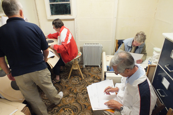 Photograph shows the hard working team of scorers busily verifying the shots and scores.
