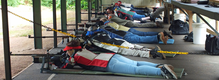 Photograph shows competitors settling down in their positions on the firing line.