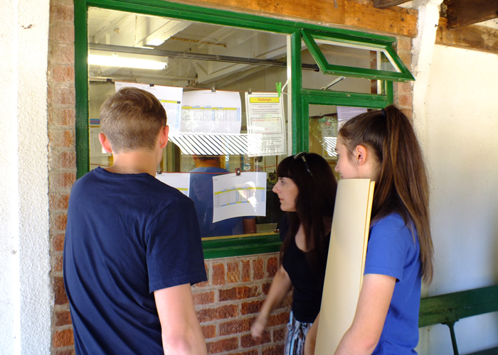 Photograph shows competitors eagerly checking their scores as they are published in the office window.