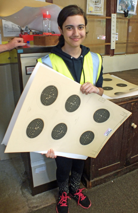 Photograph shows a very willing young volunteer presenting yet another batch of targets for scoring.