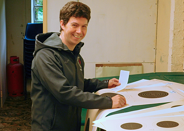 Photograph shows Richard Hemingway carefully affixing stickers to his targets before the competition begins.