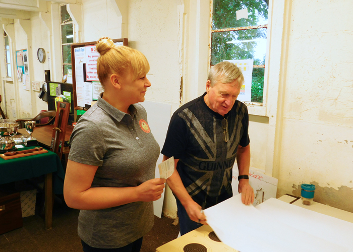 Photograph shows two of the many valued officials on duty at the event in the process of preparing the targets.