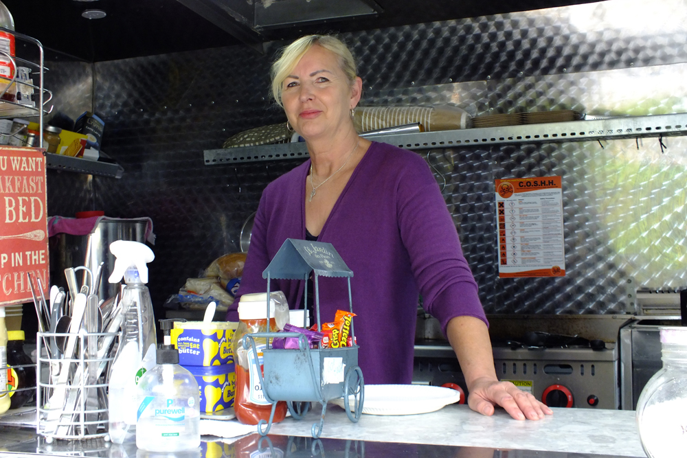 Photograph shows Sandra Williams, proprietor of San's Funky Kitchen, preparing to provide a tempting array of tasty treats.