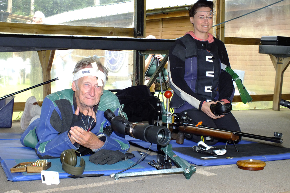 Photograph shows the last minute preparations for two of the many competitors on the firing line.