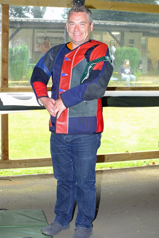 Photograph shows a competitor getting ready for action, as he does-up the buttons on his shooting jacket. Very smart too! 