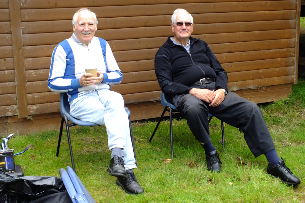 Photograph shows two gents taking in the occasion prior to making their moves onto the firing line.