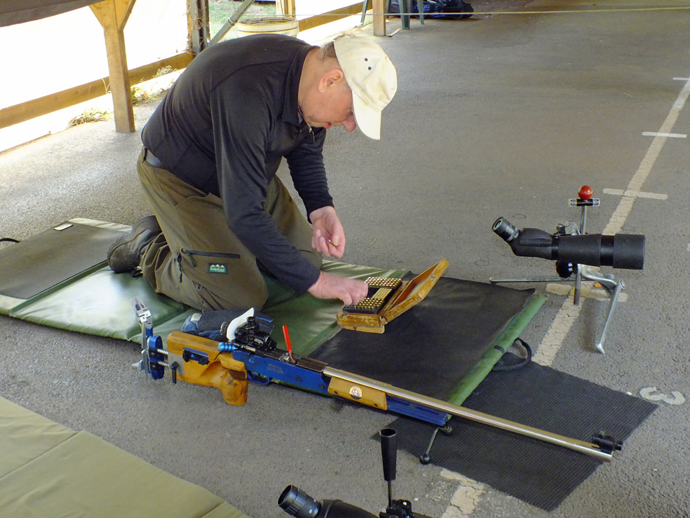 Photograph shows Brian Parker getting down to business with the final stages of readying his kit on the firing line
