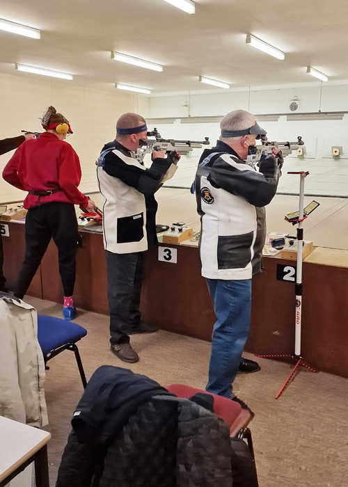 Photograph shows David Walker, pictured centre, and Alan Whitmore, pictured right, competing on the firing point during the 10 Metres Air Rifle Competition.